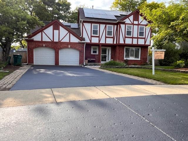 10 Chestnut Ct E, Buffalo Grove, IL 60089 - english style home featuring solar panels, asphalt driveway, a garage, brick siding, and a front yard