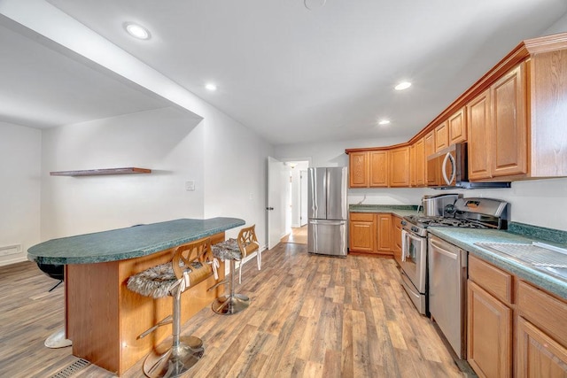 11334 S Central Park Ave, Chicago, IL 60655 - kitchen featuring appliances with stainless steel finishes, a kitchen breakfast bar, light wood-style flooring, recessed lighting, and dark countertops