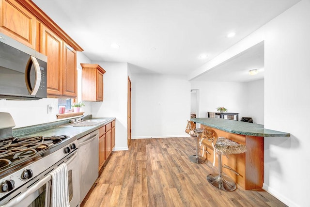11334 S Central Park Ave, Chicago, IL 60655 - kitchen featuring appliances with stainless steel finishes, a breakfast bar, light wood-style floors, recessed lighting, and brown cabinetry