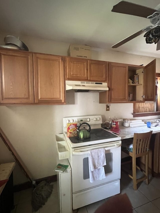 8723 S Hermitage Ave, Chicago, IL 60620 - kitchen featuring white electric range oven, under cabinet range hood, light tile patterned floors, a ceiling fan, and brown cabinetry