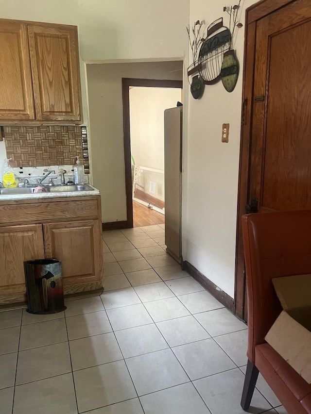 8723 S Hermitage Ave, Chicago, IL 60620 - kitchen featuring light countertops, backsplash, freestanding refrigerator, light tile patterned floors, and brown cabinetry