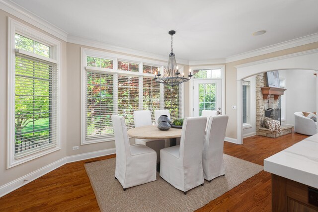 1046 Sylvan Cir, Naperville, IL 60540 - dining area with a chandelier, crown molding, dark wood-style floors, a stone fireplace, and arched walkways
