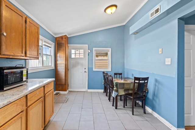 2103 N Long Ave, Chicago, IL 60639 - kitchen featuring stainless steel microwave, ornamental molding, vaulted ceiling, light countertops, and light tile patterned floors