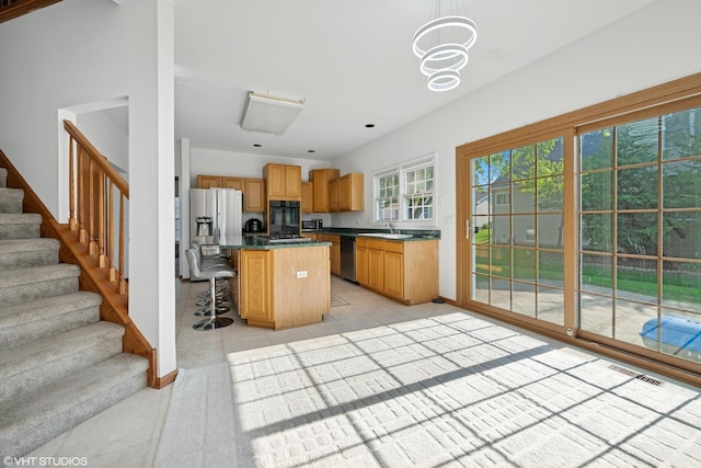 1456 Della Dr, Hoffman Estates, IL 60169 - kitchen with appliances with stainless steel finishes, a kitchen breakfast bar, a kitchen island, light tile patterned floors, and dark countertops