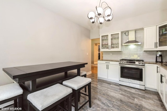 1022 Pinetree Cir N Unit 1022, Buffalo Grove, IL 60089 - kitchen featuring stainless steel gas range oven, wall chimney range hood, a chandelier, decorative backsplash, and white cabinetry