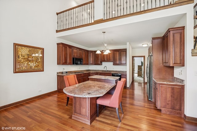 1012 Hickory Dr, Western Springs, IL 60558 - kitchen featuring black appliances, a kitchen island, light wood finished floors, a breakfast bar area, and light stone counters