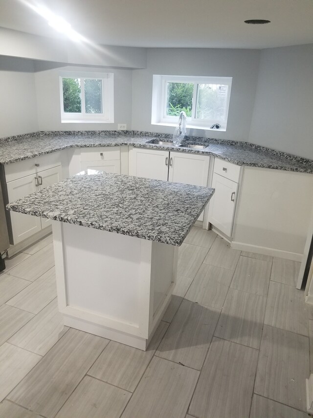 5006 W Crystal St, Chicago, IL 60651 - kitchen featuring white cabinets, light stone counters, a center island, and healthy amount of natural light