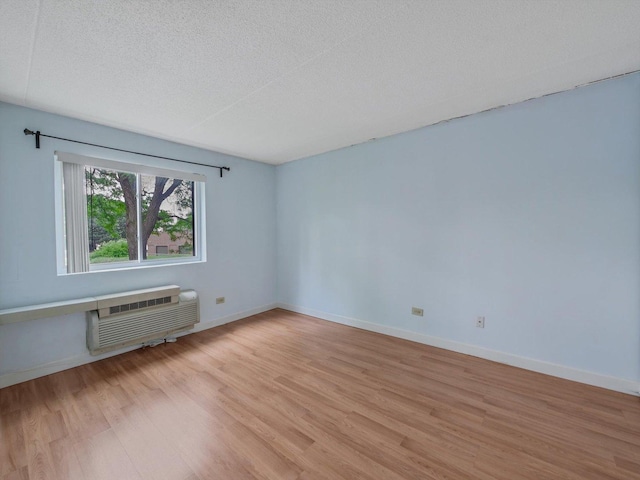 5600 Astor Ln Unit 202, Rolling Meadows, IL 60008 - empty room featuring light wood-style flooring, a wall mounted air conditioner, and a textured ceiling