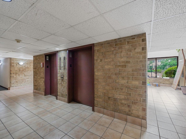 5600 Astor Ln Unit 202, Rolling Meadows, IL 60008 - spare room with a paneled ceiling, elevator, brick wall, and light tile patterned floors