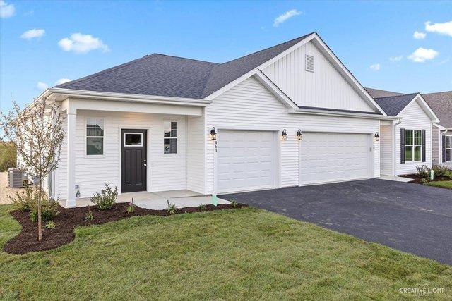 504 S Preston St, Cortland, IL 60112 - view of front of property featuring board and batten siding, a garage, asphalt driveway, a front lawn, and roof with shingles
