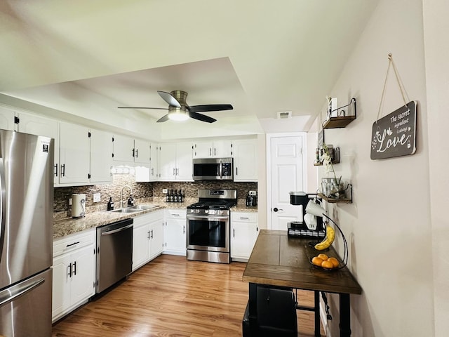 15721 Old Orchard Ct Unit 2S, Orland Park, IL 60462 - kitchen with appliances with stainless steel finishes, decorative backsplash, a ceiling fan, white cabinetry, and a tray ceiling