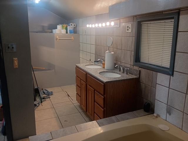 213 Edward St, Joliet, IL 60436 - bathroom with tile patterned flooring, vaulted ceiling, tile walls, double vanity, and a tub to relax in