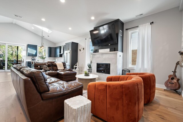 7929 N Octavia Ave, Niles, IL 60714 - living room with vaulted ceiling, recessed lighting, light wood-style floors, a tile fireplace, and a skylight