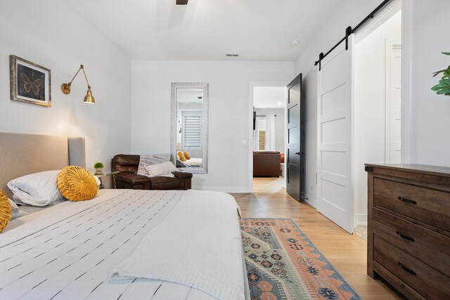 7929 N Octavia Ave, Niles, IL 60714 - bedroom featuring a barn door, light wood-style flooring, and ceiling fan