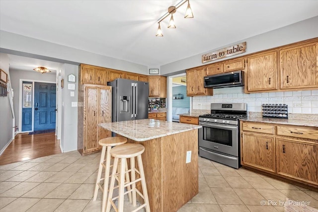 1714 Tall Tree Ln, Johnsburg, IL 60051 - kitchen featuring appliances with stainless steel finishes, light tile patterned floors, backsplash, a center island, and a kitchen breakfast bar