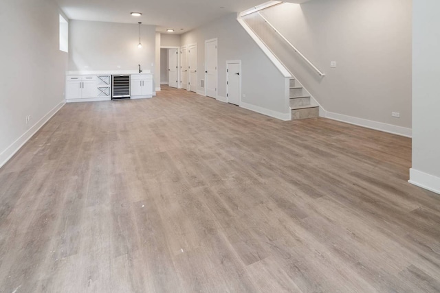 7431 W Forest Preserve Ave, Chicago, IL 60634 - unfurnished living room with beverage cooler, light wood finished floors, stairway, and bar area