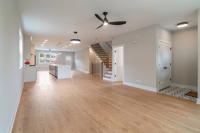 7431 W Forest Preserve Ave, Chicago, IL 60634 - unfurnished living room featuring a ceiling fan, light wood finished floors, and stairs