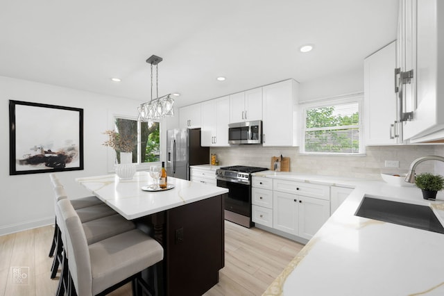 337 E Briarcliff Rd, Bolingbrook, IL 60440 - kitchen with appliances with stainless steel finishes, a center island, tasteful backsplash, a kitchen breakfast bar, and light wood finished floors