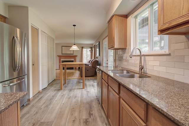 2799 Squaw Valley Trl, Aurora, IL 60503 - kitchen featuring appliances with stainless steel finishes, light wood-style floors, decorative backsplash, a fireplace, and dark stone countertops