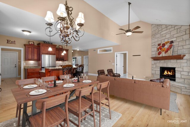 13150 S Lake Mary Dr, Plainfield, IL 60585 - dining space with light wood-type flooring, a stone fireplace, ceiling fan, vaulted ceiling, and a chandelier