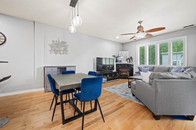 3021 W Armitage Ave Unit 201, Chicago, IL 60647 - dining room with light wood finished floors, a ceiling fan, and a tile fireplace
