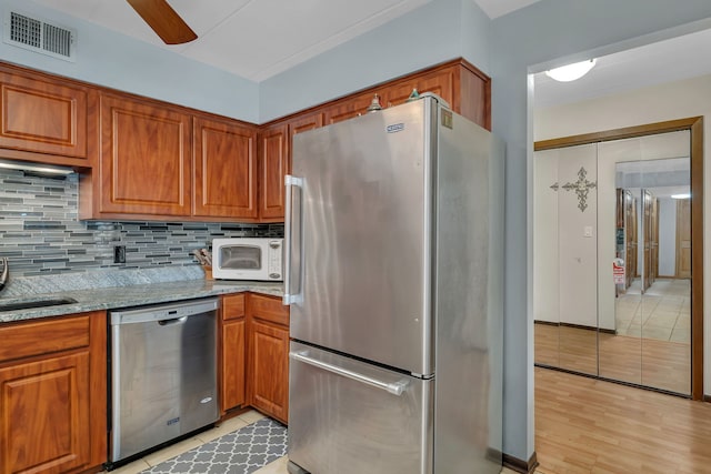 9535 S Mayfield Ave Unit 203, Oak Lawn, IL 60453 - kitchen with stainless steel appliances, decorative backsplash, light stone counters, brown cabinets, and a ceiling fan
