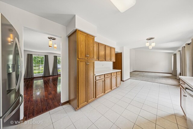 2664 Stuart Kaplan Dr, Aurora, IL 60503 - kitchen with stainless steel appliances, light tile patterned floors, brown cabinetry, and light countertops