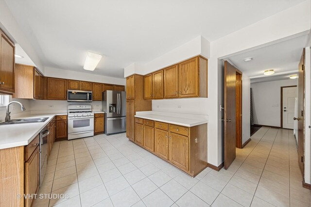 2664 Stuart Kaplan Dr, Aurora, IL 60503 - kitchen featuring appliances with stainless steel finishes, brown cabinets, light tile patterned flooring, and light countertops