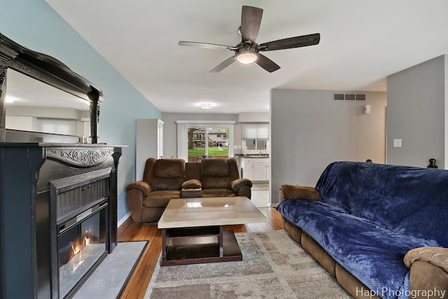1113 Rolling Lane Rd, Johnsburg, IL 60051 - living area featuring a fireplace with flush hearth, wood finished floors, and a ceiling fan