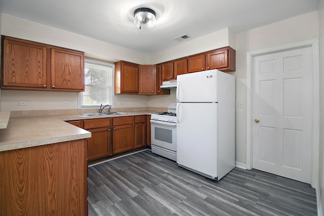 2110 E Erzinger St, Kankakee, IL 60901 - kitchen with white appliances, under cabinet range hood, brown cabinetry, and dark wood finished floors