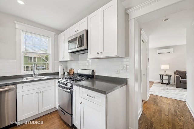 625 Park Ave, Wilmette, IL 60091 - kitchen with appliances with stainless steel finishes, dark countertops, dark wood-type flooring, white cabinetry, and a wall mounted AC