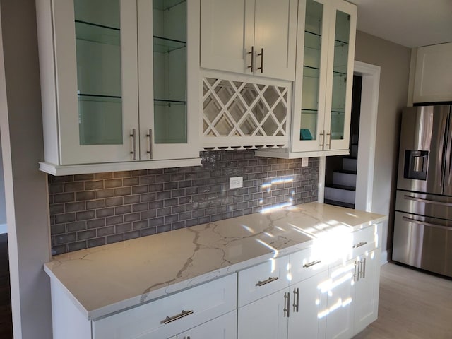 542 Laramie Ave, Wilmette, IL 60091 - kitchen with stainless steel fridge, tasteful backsplash, light stone counters, and glass insert cabinets