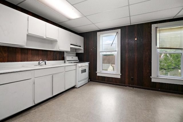 125 S Main St, Clifton, IL 60927 - kitchen with white gas range oven, under cabinet range hood, a paneled ceiling, wooden walls, and light countertops