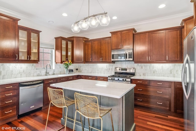 3019 W Cornelia Ave, Chicago, IL 60618 - kitchen featuring stainless steel appliances, dark wood finished floors, a kitchen island, glass insert cabinets, and ornamental molding