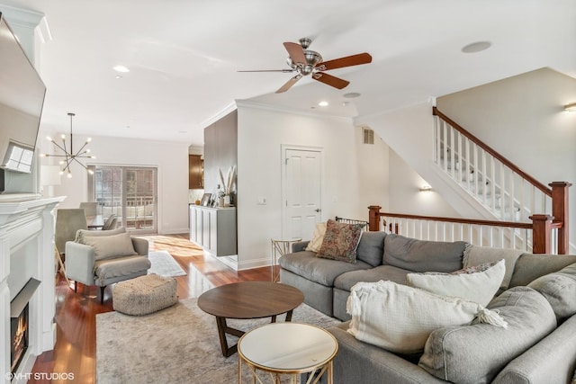 3019 W Cornelia Ave, Chicago, IL 60618 - living area featuring a warm lit fireplace, crown molding, a ceiling fan, stairs, and a chandelier