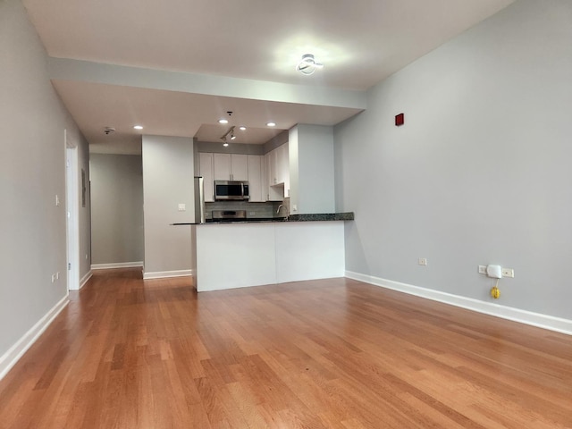 1250 S Michigan Ave Unit 703, Chicago, IL 60605 - kitchen with stainless steel microwave, light wood-type flooring, dark countertops, white cabinetry, and recessed lighting