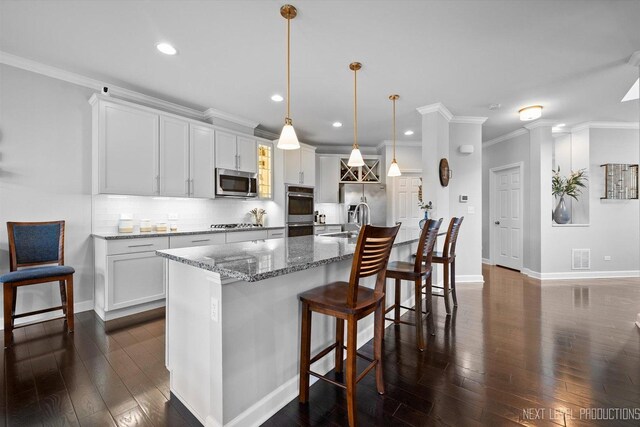 3S661 Breme Dr W, Warrenville, IL 60555 - kitchen featuring stainless steel appliances, backsplash, dark wood-style floors, a kitchen island with sink, and a breakfast bar