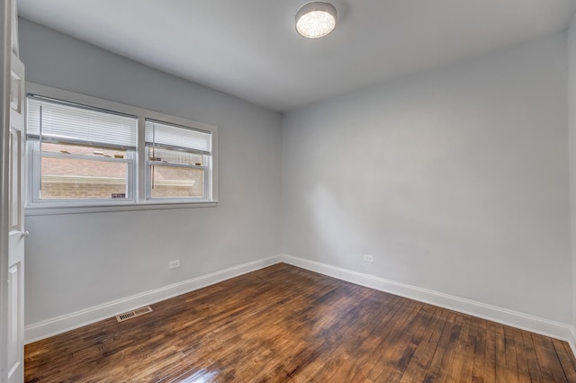empty room with baseboards and dark wood-type flooring