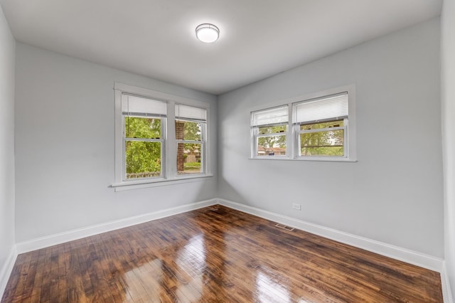 spare room with baseboards and dark wood finished floors