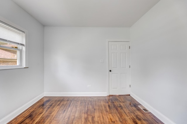 empty room with dark wood-type flooring and baseboards