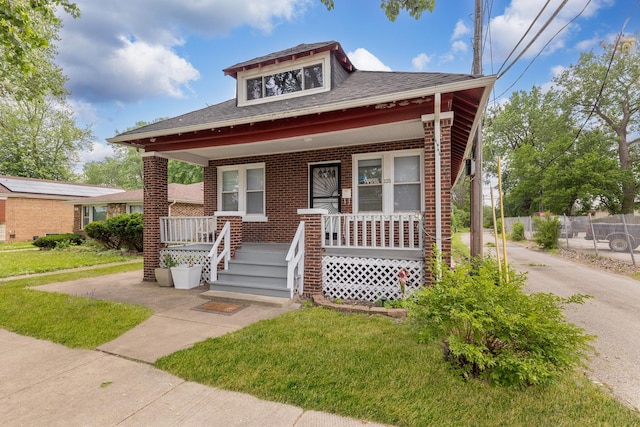 view of front of home with a porch, brick siding, a shingled roof, and driveway