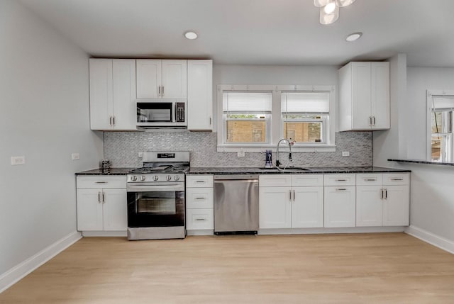 kitchen with appliances with stainless steel finishes, white cabinets, tasteful backsplash, light wood-style floors, and recessed lighting