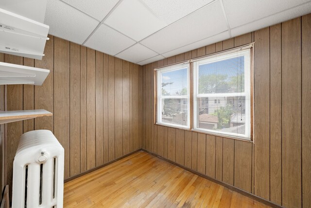 5010 N California Ave, Chicago, IL 60625 - spare room featuring a paneled ceiling, light wood-type flooring, radiator heating unit, and wooden walls
