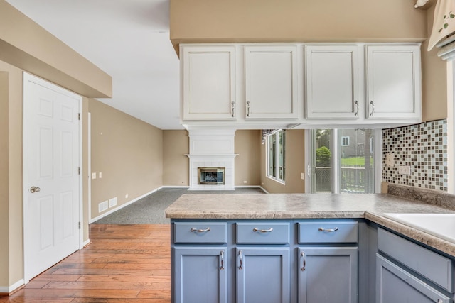 768 Fieldstone Dr, Lake Villa, IL 60046 - kitchen with light wood-type flooring, a peninsula, white cabinetry, and a fireplace