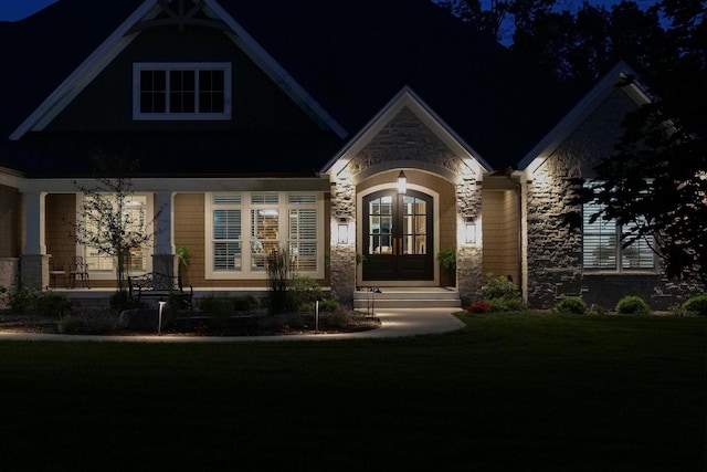 2611 Private Access 424, Mahomet, IL 61853 - exterior entry at night featuring stone siding, french doors, a yard, and a porch