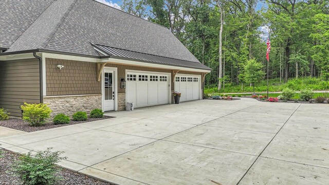 2611 Private Access 424, Mahomet, IL 61853 - view of side of home featuring driveway, roof with shingles, a standing seam roof, stone siding, and a garage