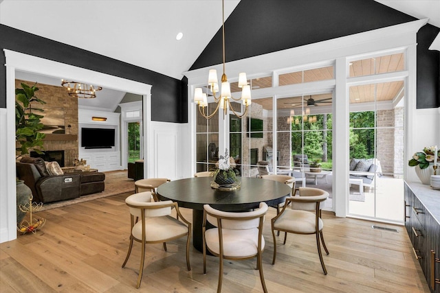 2611 Private Access 424, Mahomet, IL 61853 - dining space featuring a chandelier, light wood finished floors, a large fireplace, ceiling fan, and high vaulted ceiling
