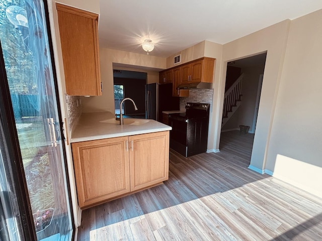 325 Shadowbend Dr, Wheeling, IL 60090 - kitchen with black electric range, under cabinet range hood, a peninsula, decorative backsplash, and light countertops