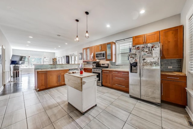 2150 W Coulter St, Chicago, IL 60608 - kitchen featuring stainless steel appliances, brown cabinetry, a peninsula, light countertops, and backsplash