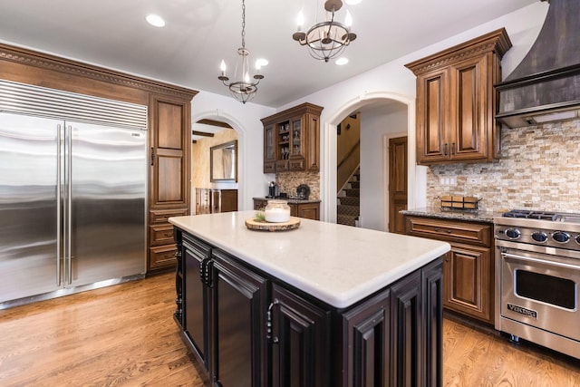 7N230 Sims Ln, Saint Charles, IL 60175 - kitchen featuring high end appliances, custom exhaust hood, arched walkways, backsplash, and hanging light fixtures